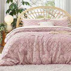 a bed with pink bedspread and pillows in a white room next to potted plants