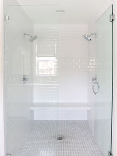 an image of a bathroom with white tile and glass shower doors, including the floor