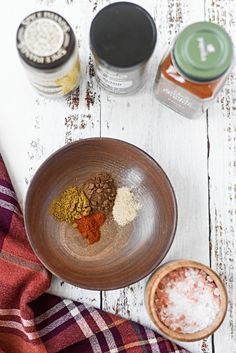 spices and seasonings in small bowls on a white wooden table next to an orange towel