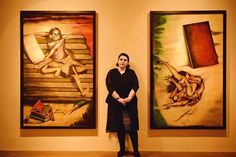 a woman standing in front of two paintings