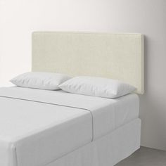 a white bed with two pillows on top of it and a night stand next to it