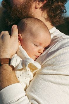 a man holding a baby in his arms with the arm around him's head