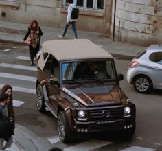 the car is parked on the side of the road with people walking around in front of it