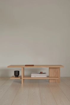 a wooden table sitting on top of a hard wood floor next to a white wall