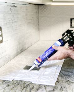 a man holding a paint roller in his hand and painting the wall with white paint