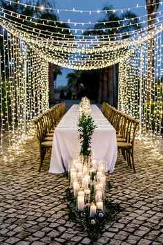 a long table with candles and greenery is set up in the middle of an outdoor area