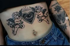 a woman's stomach with tattoos on it and an eye in the center, surrounded by cherubs