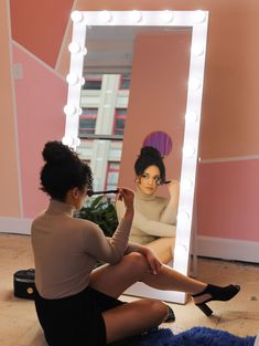 a woman sitting on the floor in front of a mirror