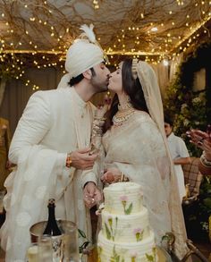 a newly married couple kissing each other in front of a cake with lights on the ceiling