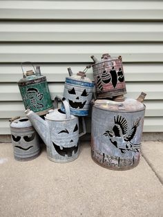 four old tin canisters with birds painted on them sitting in front of a building