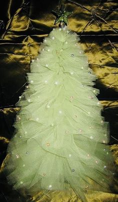 a green christmas tree with white lights on it's bottom and the top is made out of tulle