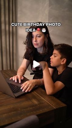 a woman and boy sitting at a table with a laptop computer in front of them