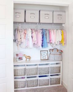 an organized closet with baskets and clothes hanging on the wall, along with baby's clothing