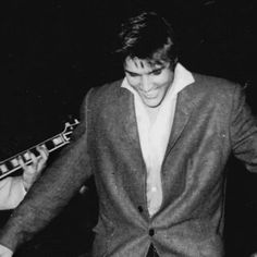 black and white photograph of two men playing guitar together, one man is wearing a suit and the other has a tie