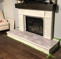 a white fireplace with green tape around it