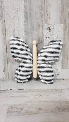 a black and white striped butterfly on a wooden wall with wood pegs attached to it