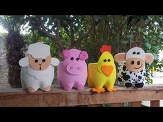 five farm animals sitting on top of a wooden rail next to a tree and bushes