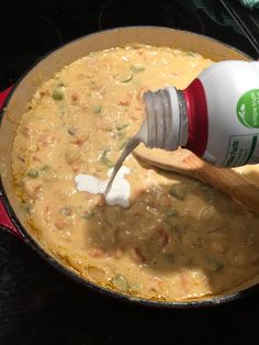 a person pouring milk into a pot filled with food