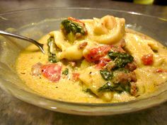 a pasta dish with spinach, ham and cheese in a bowl on a table