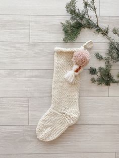 a white knitted stocking with a pink pom - pom hanging from it