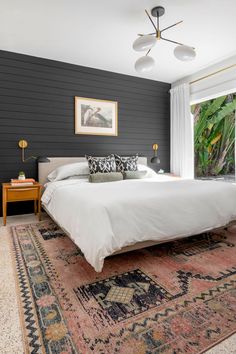 a large bed sitting in a bedroom on top of a rug next to a window