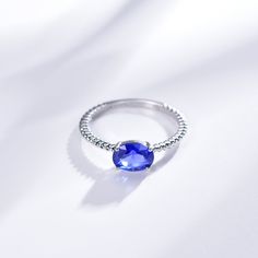 a ring with a blue stone in the middle on a white surface, close up