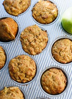 muffins and an apple sitting in a muffin tin next to each other