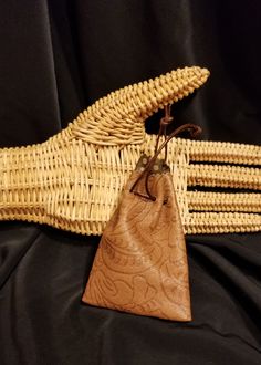 two pieces of woven material are sitting on a black cloth with a brown leather pouch