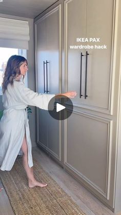 a woman in a bathrobe is opening the refrigerator door and pointing at it