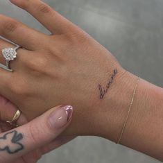 a woman's hand with a small diamond ring on her left wrist that says love