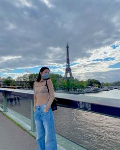 a woman wearing a face mask standing in front of the eiffel tower