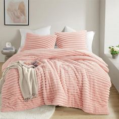 a bed with a pink comforter and pillows