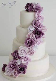 a three tiered white cake with purple flowers on top