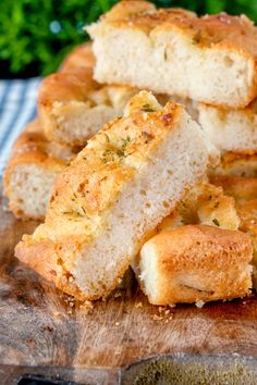 several pieces of bread sitting on top of a wooden cutting board next to some parsley