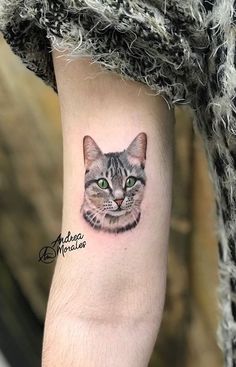 a cat with green eyes is shown on the arm and it's head has been drawn