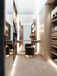 a walk in closet with several shelves and foot stools on either side of the room