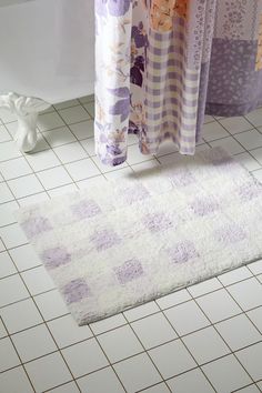 a bathroom with white tiles and purple rugs