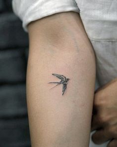 a small bird tattoo on the left arm