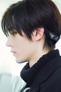 a young man with black hair has a cell phone in his ear and is looking off to the side