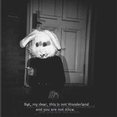 a bunny is standing in front of a door wearing a black shirt and holding a drink