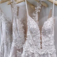 three wedding gowns are hanging on a rack