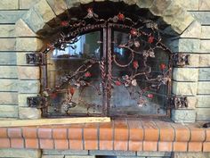 an iron fireplace screen with vines and flowers on the front, sitting on a brick mantle