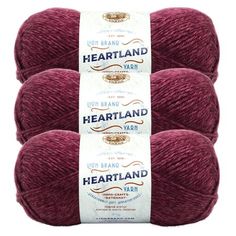 three skeins of red yarn with the words heartland written on each ball