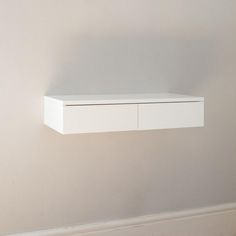 a white shelf sitting on the wall next to a window