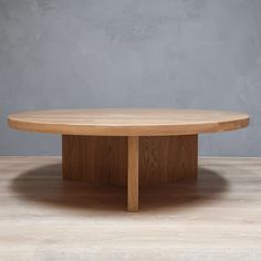 a round wooden table sitting on top of a hard wood floor covered in light colored paint