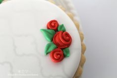 two decorated cookies on top of each other with red and green frosting roses in the middle