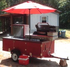 an outdoor bbq is set up in front of a shed with an umbrella over it