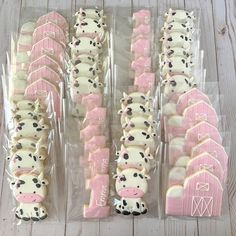 there are many decorated cookies in the shape of farm animals on plastic trays with pink and white frosting