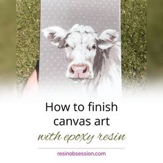 a person holding up a canvas with a painting of a cow on it's face