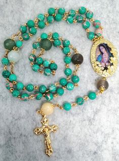 Beautiful Rosary dedicated to the Holy Virgin of Guadalupe. This precious rosary is made of glass beads that imitate the turquoise stone. Everything is connected by hand to the rule of art, brass wire that guarantees its durability. To see more Rosaries: labottegadelrosario.etsy.com Turquoise Rosary With Round Beads, Spiritual Turquoise Rosary With Round Beads, Bohemian Gold Rosary With 8mm Beads, Gold Bohemian Rosary With 8mm Beads, Mexican Style Dresses, Beautiful Rosary, Virgin Of Guadalupe, Everything Is Connected, Our Lady Of Guadalupe